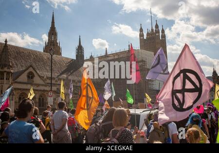 Extinction Rebellion Demonstranten marschieren bei den Demonstrationen 2020 mit bunten Fahnen an den Houses of Parliament vorbei. VEREINIGTES KÖNIGREICH Stockfoto