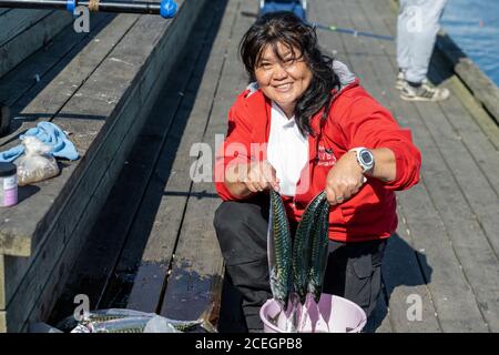 Eine aktive asiatische Frau in ihren 50ern zeigt eine frische Makrelenfang Stockfoto