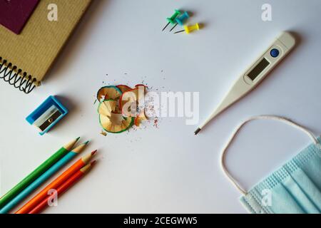 Schulbedarf, eine medizinische Maske und ein Thermometer - zurück zum Schulkonzept in der neuen Normalität Stockfoto