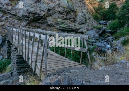 Holz- und Steinbrücke über den Fluss Guarnon im Naturpark Sierra Nevada. Stockfoto