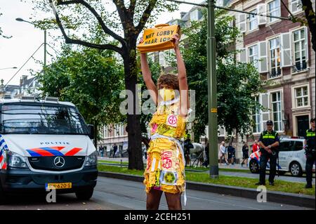 Den Haag, Niederlande. September 2020. Eine XR-Frau, die während der Modenschau mit ihrer Tasche in der Nähe der niederländischen Polizei posiert.vor dem Repräsentantenhaus in Den Haag wurde eine "XR-Modenschau" durchgeführt. Modelle trugen gelbe, schwarze und weiße bunte Second-Hand-Outfits, um die Kollektivität der Bienen zu symbolisieren, um zu zeigen, dass Denken und Arbeiten zusammen uns aus dieser Krise helfen können. Kredit: SOPA Images Limited/Alamy Live Nachrichten Stockfoto