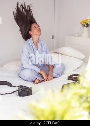 Junge Frau, die auf dem Bett sitzt Stockfoto