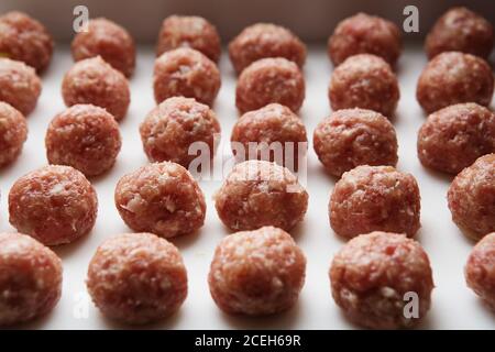 Frisch gekochte rohe Fleischbällchen liegen auf einem weißen Plastikküchenbrett. Stockfoto