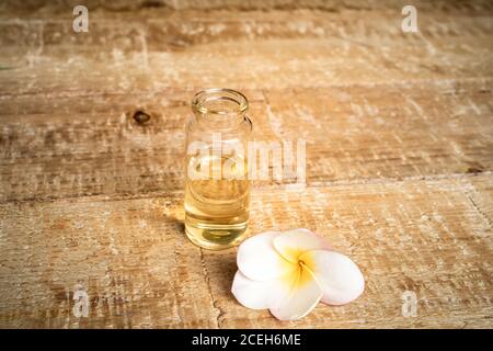 Nahaufnahme eines ätherischen Öls in einer kleinen Glasflasche mit Frangipani-Blumen auf Holzhintergrund. Selektiver Fokus und Kopierbereich für Text. Natürlicher Kosmos Stockfoto