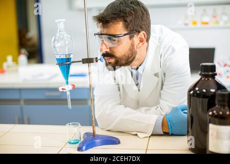 Forscher arbeiten mit blauer Flüssigkeit am Separationstrichter in der Labor Stockfoto
