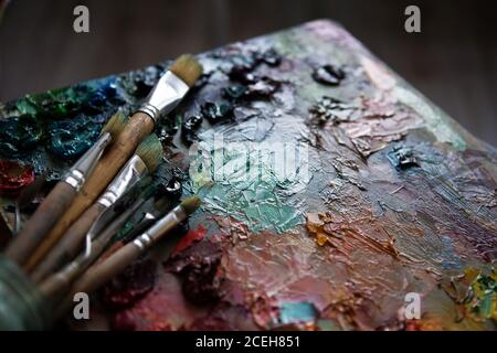 Künstler Pinsel und Ölfarben auf Holzpalette. Makro Künstler Palette, Textur gemischt Ölfarben in verschiedenen Farben und Sättigung. Palette mit pa Stockfoto