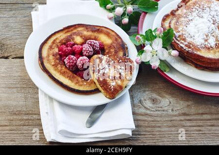 Pfannkuchen mit Himbeeren zum Frühstück auf einem Holztisch. Stockfoto