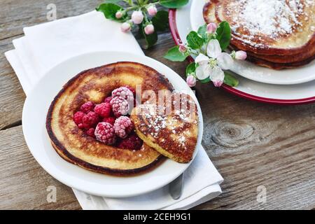 Pfannkuchen mit Himbeeren zum Frühstück auf einem Holztisch. Stockfoto