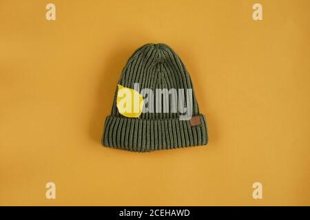 Khaki grün Strickmütze und Herbstblatt auf gelbem Hintergrund. Stockfoto