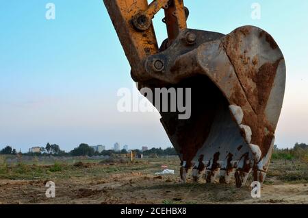 Große Eisenkelle aus Metall. Baggereimer zum Graben einer Grube und eines Rohrleitungsgrabens auf einer Baustelle. Gewerbliche und öffentliche Bauaufträge, tr Stockfoto