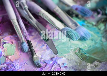 Künstler Pinsel und Ölfarben auf Holzpalette. Makro Künstler Palette, Textur gemischt Ölfarben in verschiedenen Farben und Sättigung. Palette mit pa Stockfoto