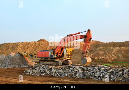 Schwerer Raupenbagger last Stein, mit alten Asphalt oder Beton Abfall in eine Mobile Backenbrecher Maschine. Die Zerkleinerung und Verarbeitung in Kies für Recycling Stockfoto