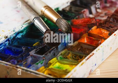 Künstler Pinsel und Aquarellfarben auf Palette. Vintage stilisierte Foto von Pinsel Nahaufnahme und Künstler Palette. Verwendete Palette mit Pinsel Stockfoto