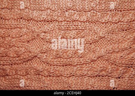 Wollpullover oder Schal Textur Nahaufnahme. Gestrickter Jersey-Hintergrund mit Reliefmuster. Zöpfe im Maschinenstrickmuster. Wolle handgestrickt oder mach Stockfoto