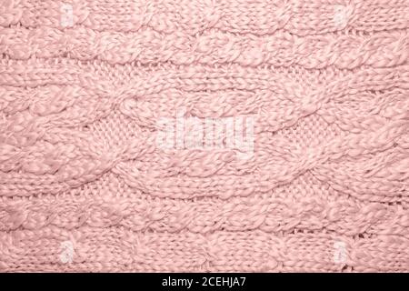 Wollpullover oder Schal Textur Nahaufnahme. Gestrickter Jersey-Hintergrund mit Reliefmuster. Zöpfe im Maschinenstrickmuster. Wolle handgestrickt oder mach Stockfoto