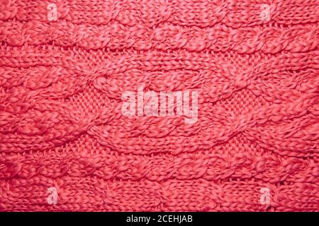 Wollpullover oder Schal Textur Nahaufnahme. Gestrickter Jersey-Hintergrund mit Reliefmuster. Zöpfe im Maschinenstrickmuster. Wolle handgestrickt oder mach Stockfoto
