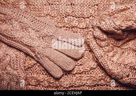 Set aus Wollpullover oder Schal, Hut und Handschuhe Textur aus nächster Nähe. Gestrickter Jersey Stoff Hintergrund mit Reliefmuster. Zöpfe in Maschinenstrickpastete Stockfoto