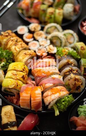 Verschiedene Sushi-Gerichte auf dunklem Hintergrund. Blick von oben auf Meeresfrüchte, verschiedene Maki-Brötchen Stockfoto