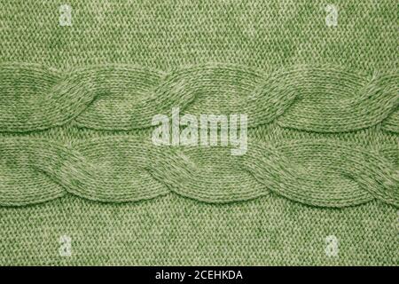 Wolle Pullover Textur Nahaufnahme. Gestrickter Jersey-Hintergrund mit Reliefmuster. Zöpfe im Maschinenstrickmuster Stockfoto
