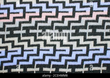 Ein geometrisches Muster auf einem Strickstoff. Weihnachtliche Zierstrick. Gestrickter Pullover im Hintergrund. Echt gestrickt Stoff texturierter Hintergrund Stockfoto
