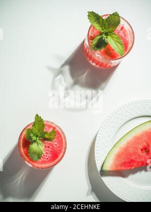 Zwei Gläser Wassermelone rot frischen Smoothie mit Minze auf weißem Tisch. Overhead-Aufnahme mit Kopierplatz. Minimalismus. Stockfoto
