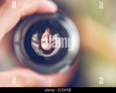 Nahaufnahme des Hand-Halteobjektivs mit umgekehrtem Bild einer lächelnden Frau auf unscharfem Hintergrund Stockfoto
