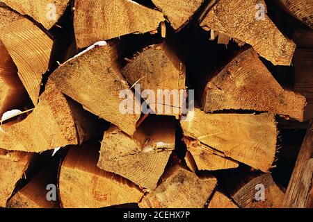 Der Stapel des verschneiten Brennholzes auf altem hölzernen Hintergrund. Holzstücke, Baumkronen im Freien für Kamin oder Mantel, Textur oder Hintergrund gelagert. Stockfoto