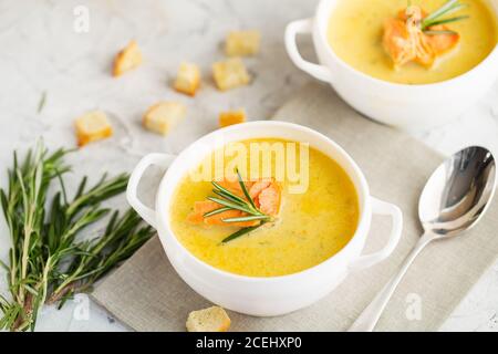 Fischsahnesuppe mit Lachs, Käse, Kartoffeln und Kräutern in weißen Suppenschalen. Stockfoto