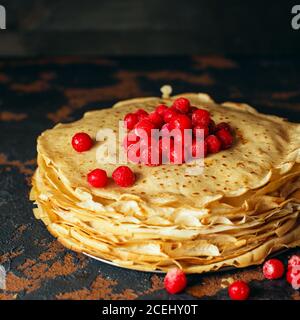 Russische Pfannkuchen mit Beeren vor dunklem Hintergrund. Pancake Week - das alte slawische Fest des Sehens aus dem Winter, von dem der Brauch Stockfoto