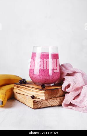 Bananenbeer Smoothie im Glas auf dem hölzernen Servierbrett. Frisches und gesundes Frühstück Stockfoto
