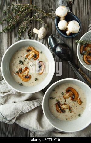 Zwei Schüsseln mit köstlicher Pilzsuppe auf Holztisch. Flache Lagenzusammensetzung. Food-Fotografie Stockfoto