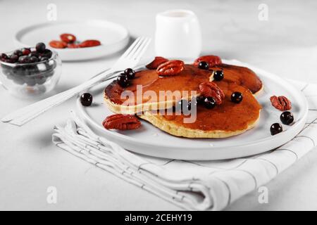 Gesundes Sommerfrühstück, hausgemachte klassische amerikanische Pfannkuchen mit frischen Beeren, Nüssen und Honig, Morgen hellgrau Stein Hintergrund copy space Stockfoto