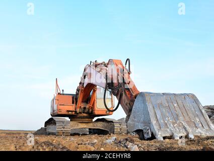 Red Raupenbagger bei einem Tagebau. Zerkleinerung und Recycling auf der Baustelle. Straßenarbeiten. Spezielle schwere Baumaschinen für Straße Nachteile Stockfoto