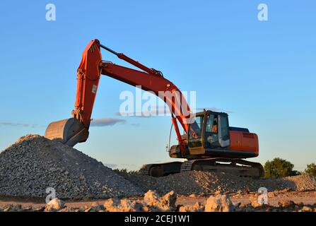 Schwerbagger in einer Arbeit in Granitbruch lädt alte Betonsteine für Zerkleinerung und Recycling zu Kies oder Zement. Spezielle schwere Konstruktion Stockfoto