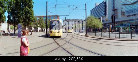 Manchester, Großbritannien - 11. August 2020: Eine Frau überquert die Straßenbahn in Piccadilly Gardens. Stockfoto