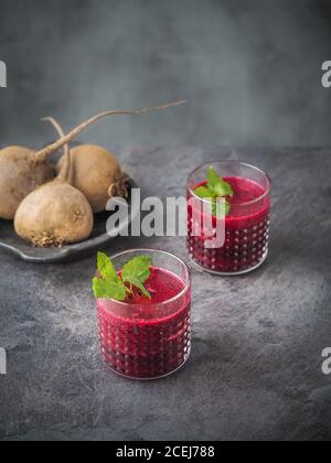 Zwei Gläser Rote Beete Smoothie mit Minzblättern auf dunklem Tisch. Speicherplatz kopieren. Minimalismus Stockfoto