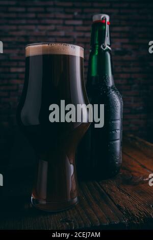 Stout Bier in Glas abd Flasche auf dunklem Hintergrund Stockfoto