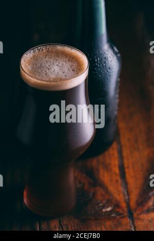 Stout Bier in Glas abd Flasche auf dunklem Hintergrund Stockfoto