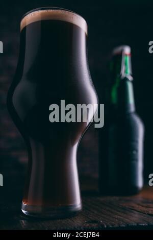 Stout Bier in Glas abd Flasche auf dunklem Hintergrund Stockfoto