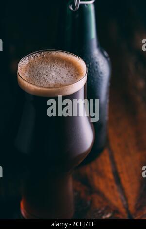 Stout Bier in Glas abd Flasche auf dunklem Hintergrund Stockfoto