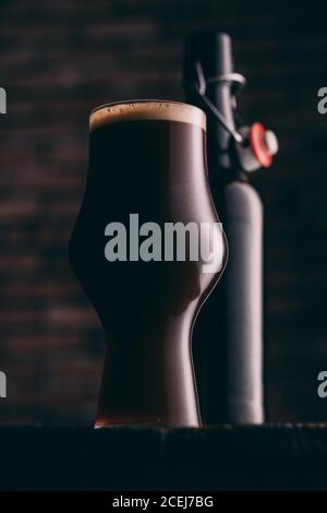 Stout Bier in Glas abd Flasche auf dunklem Hintergrund Stockfoto