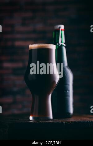 Stout Bier in Glas abd Flasche auf dunklem Hintergrund Stockfoto