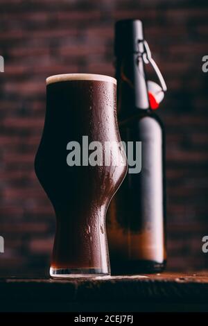 Stout Bier in Glas abd Flasche auf dunklem Hintergrund Stockfoto