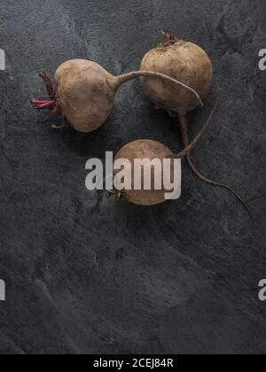 Drei frische reife Rote Beete auf dunklem Tisch. Overhead-Aufnahme mit Kopierplatz. Stockfoto