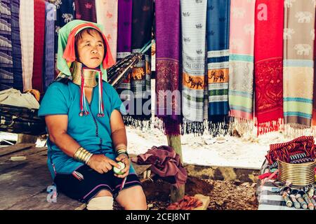 Frau mit langem Hals webt Tuch vor ihrem Haus im Stammesdorf Nord-Thailand. Stockfoto