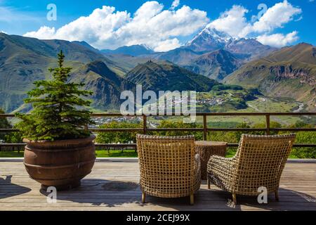 Schöne Aussicht von der Terrasse Café mit Blick auf den hohen Gipfel Kasbek, Kaukasus Berge und Gergeti Trinity Church Tsminda Sameba, Heilig Stockfoto