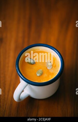 Kürbissuppe in einem Becher auf Holztisch mit Kürbis Seeds Stockfoto
