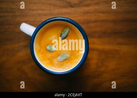 Kürbissuppe in einem Becher auf Holztisch mit Kürbis Seeds Stockfoto