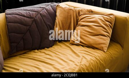 Modernes Wohnzimmerdesign mit gelbem Sofa und braunen Kissen - Nahaufnahme Stockfoto