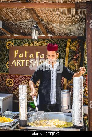 MITTELALTERLICHER MARKT - PUEBLA DE SANABRIA - ZAMORA - SPANIEN - AGOUST 13, 2017: Junger Mann in traditioneller Kleidung, der traditionelle Lebensmittel auf dem Markt herstellt Stockfoto